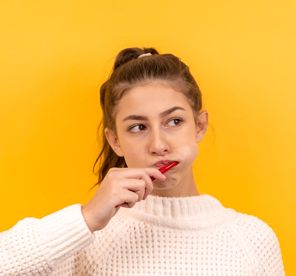 knightstreetdentists.com.au | Young woman brushing her teeth against a bright yellow background.