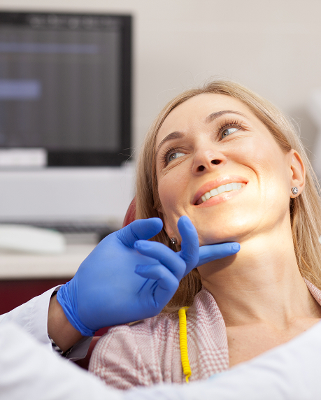 knightstreetdentists.com.au | Smiling patient in dental chair as dentist gently examines her jaw.